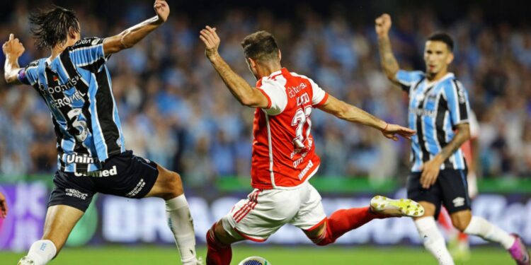 Lucas Alario, do Internacional, e Pedro Geromel, do Grêmio, disputam a posse de bola em partida válida pelo Campeonato Brasileiro