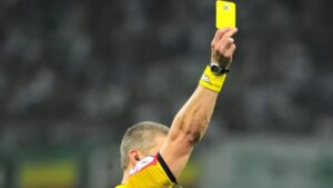 Juiz mostra um cartão amarelo durante partida de futebol
