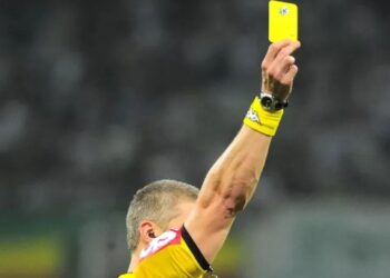Juiz mostra um cartão amarelo durante partida de futebol