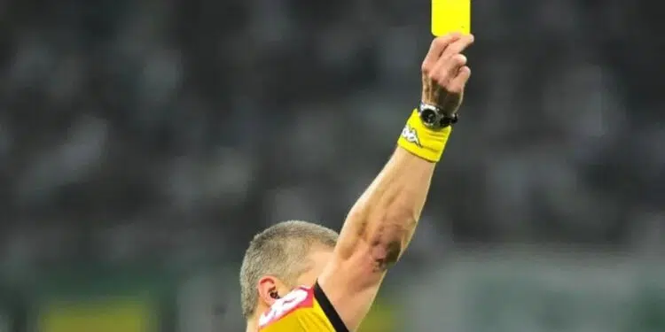Juiz mostra um cartão amarelo durante partida de futebol
