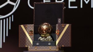 Foto do troféu Bola de Ouro sendo apresentado dentro de uma mala do Louis Vuitton
