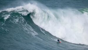 Foto do surfista Willyam Santana pegando uma onda gigante em Nazaré, Portugal
