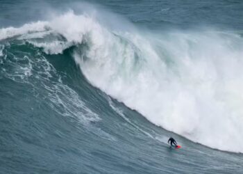 Foto do surfista Willyam Santana pegando uma onda gigante em Nazaré, Portugal