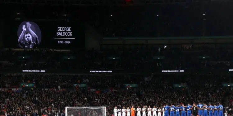 Jogadores de Inglaterra e Grécia se reúnem no meio do campo para prestar um minuto de silêncio, em homenagem a George Baldock