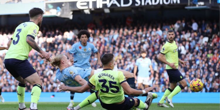 Haaland caindo e chutando a bola no jogo entre Manchester City e Southampton
