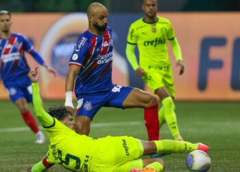 Thaciano, do Bahia, carrega a bola enquanto Gustavo Gómez, do Palmeiras, dá um carrinho tentando tirá-la