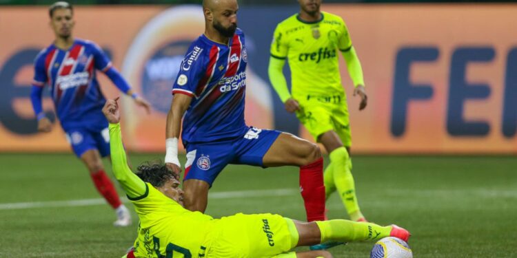 Thaciano, do Bahia, carrega a bola enquanto Gustavo Gómez, do Palmeiras, dá um carrinho tentando tirá-la