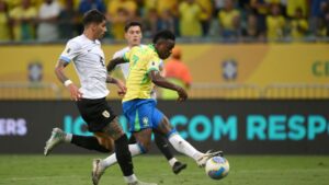 Vini Jr., da Seleção Brasileira, carrega a bola enquanto José Gímenez, do Uruguai, o marca