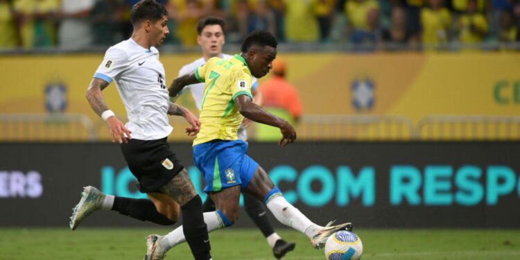 Vini Jr., da Seleção Brasileira, carrega a bola enquanto José Gímenez, do Uruguai, o marca