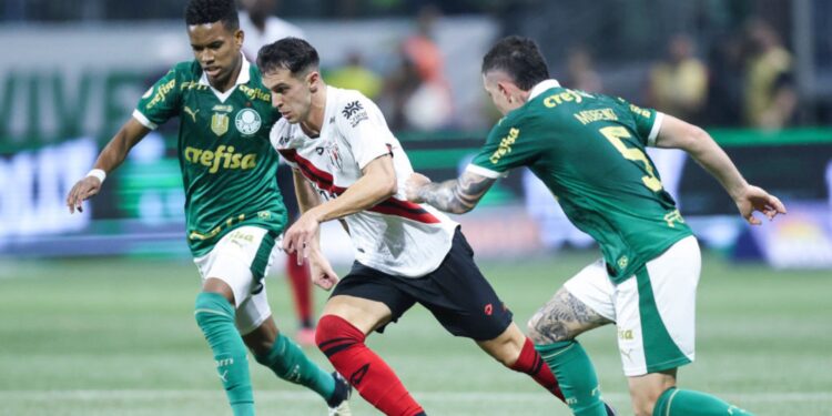 Shaylon, do Atlético-GO, tenta manter a posse de bola enquanto é marcado por Estêvão e Aníbal Moreno, do Palmeiras.
