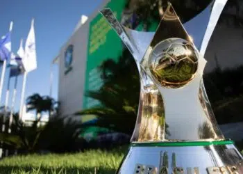 Foto da taça do Brasileirão, com a sede da CBF ao fundo