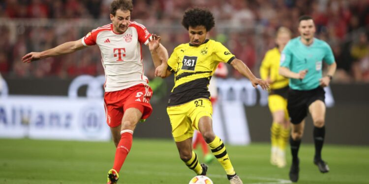 Adeyemi, do Borussia Dortmund, carrega a bola enquanto Goretzka, do Bayern de Munique, o marca