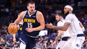 Nikola Jokic, do Denver Nuggets carrega a bola enquanto Daniel Gafford, do Dallas Mavericks, tenta marcá-lo