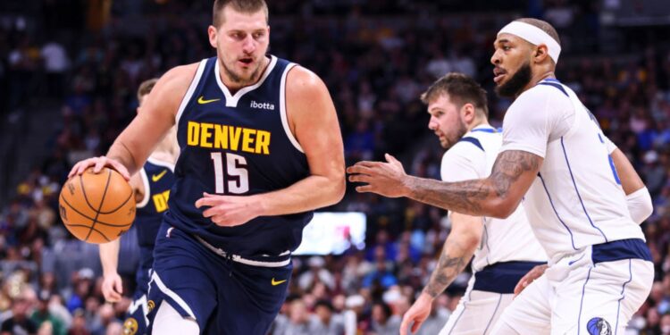 Nikola Jokic, do Denver Nuggets carrega a bola enquanto Daniel Gafford, do Dallas Mavericks, tenta marcá-lo