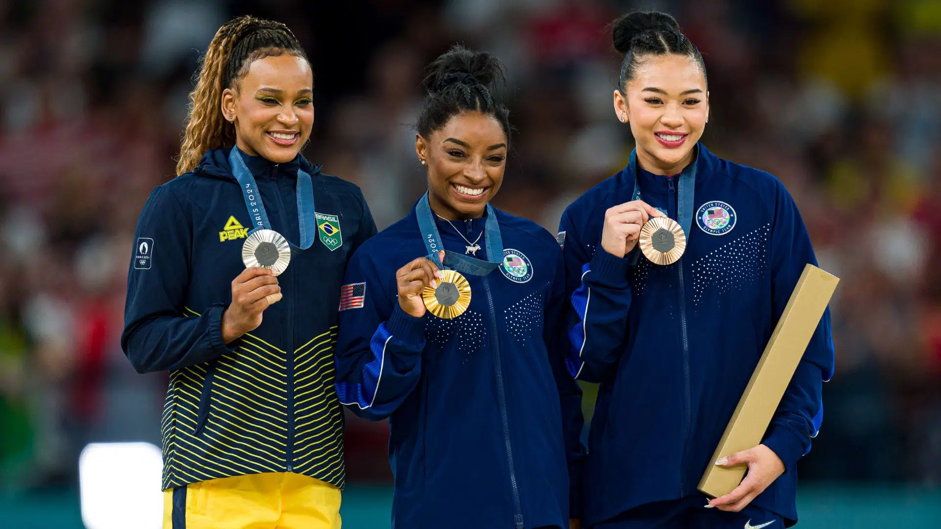 Rebeca Andrade no pódio do individual geral, ao lado de Simone Biles e Sunisa Lee