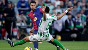 Ferran Torres, do Barcelona, tenta passar a bla enquanto é marcado por Marc Bartra, do Real Betis