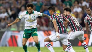 Felipe Anderson, do Palmeiras, carrega a bola enquanto é marcado por jogadores do Fluminense, em partida válida pelo Brasileirão