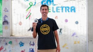 Caio Bonfim, atleta de marcha atlética, posa com medalha durante visita ao Instituto Gol de Letra