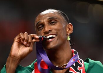 Alison dos Santos mordendo a medalha de prata