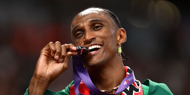 Alison dos Santos mordendo a medalha de prata