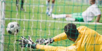 Goleiro pulando na bola em partida de futebol - Créditos: depositphotos.com / ArturVerkhovetskiy