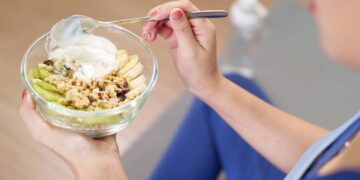 Mulher com roupas de treino físico se alimentando antes de atividades - Créditos: depositphotos.com / pichsakul