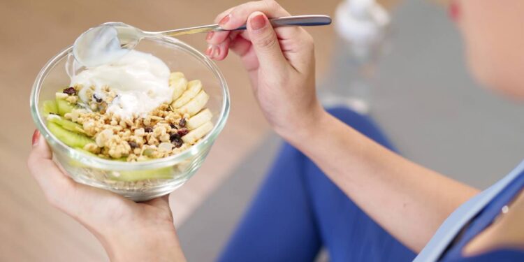 Mulher com roupas de treino físico se alimentando antes de atividades - Créditos: depositphotos.com / pichsakul