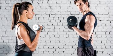 Casal realizando treino de bíceps com halteres - Créditos: depositphotos.com / DimaGavrish