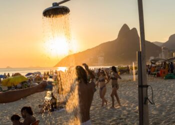 Pessoas tomando banho em chuveiro na praia do Rio de Janeiro