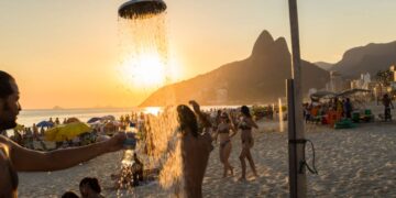 Pessoas tomando banho em chuveiro na praia do Rio de Janeiro