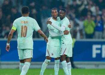 Olise comemorando gol pela França ao lado de Dembelé e Mbappé