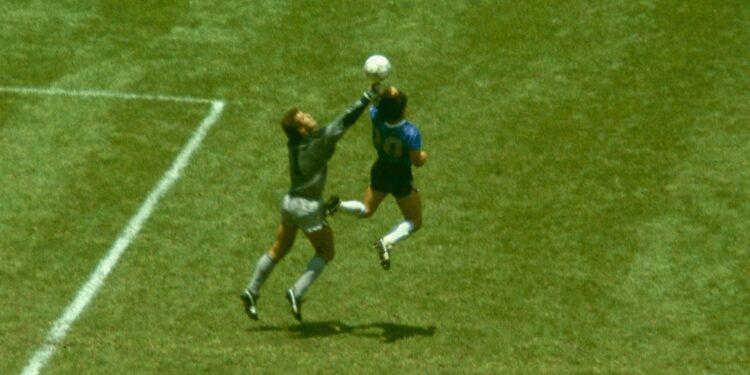 Maradona marca com a mão contra a Inglaterra em 1986, no lance que ficou conhecido mundialmente como "La Mano de Dios"